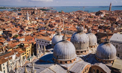 The view of the domes of St Marks Basilica as seen from the top of the Campanile (Belltower). Beyond the cathedral is the jumble of old streets and buildings of Venice.